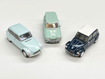 trois petites voitures miniatures sont posées les unes à côté des autres sur une surface blanche