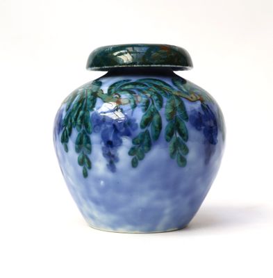 a blue vase with a green lid sitting on a white surface