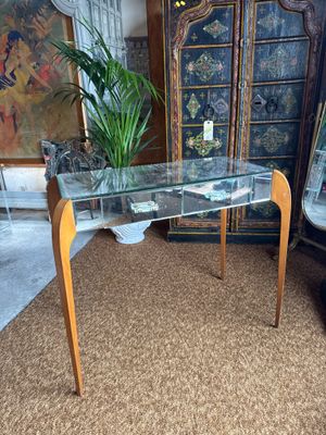 a glass table with a plant on it in the middle of a room
