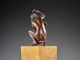 an image of a bronze statue of a man kneeling on a marble block