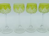 six verres à vin jaunes alignés sur une surface blanche