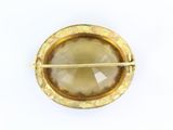 yellow gold tone broochle with a faceted stone in the center of it