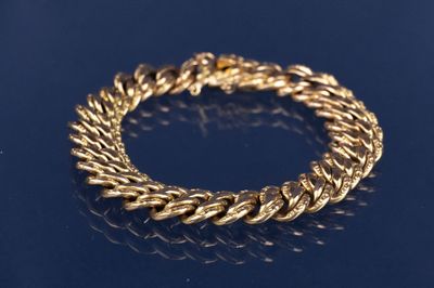 un gros plan d'un bracelet en or sur un fond bleu