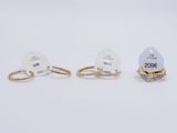 three gold rings with diamonds and a price tag on a white background