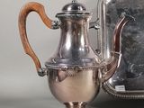 a silver tea pot sitting next to a silver tray
