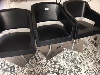 trois chaises noires placées les unes à côté des autres sur un sol carrelé