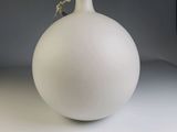 a white vase with a flower in it sitting on a table