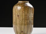a brown vase sitting on a white table with a black background
