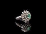 an emerald and diamond ring on a black surface
