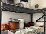 a metal shelf with dishes and pans on it in a kitchen