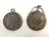 two silver coin charms with a picture of a man and a woman on them