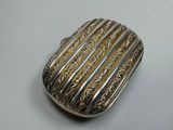 an image of a silver and gold broochle on a white surface