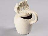 a white vase with a handle that has a wave design on it