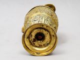 a gold vase that is sitting on a white surface