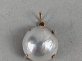 a close up of a white pearl pendant on a white surface