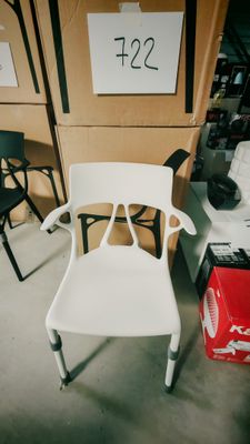 une chaise blanche dans une pièce où se trouvent de nombreuses chaises