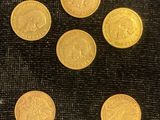 six pièces d'or sont disposées en cercle sur un tissu noir