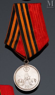 deux médailles et une médaille posée sur une table, ornée d'un ruban rouge