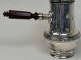 a silver coffee pot with a wooden handle on a white table