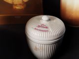 a white container with a lid sitting on a table next to a candle