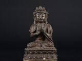 une statue en bronze représentant un Bouddha sur fond noir
