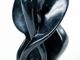une sculpture noire représentant un objet en forme de cœur sur fond blanc