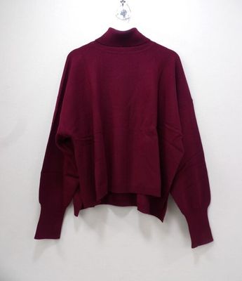 a maroon sweater hanging on a hanger against a white wall