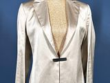 shiny silver jacket on a mannequin stand against a blue background