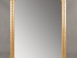 un grand miroir dans un cadre doré, orné d'un motif décoratif