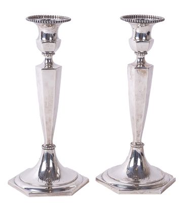 paire de bougeoirs plaqués argent sur un socle, sur fond blanc