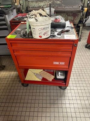 un établi rouge sur lequel se trouve un seau rempli d'outils