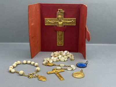 a red book with a cross, rosary, and other religious items