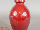 a red vase with a light on it next to a string