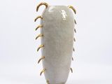 an image of a white vase with gold spikes on it