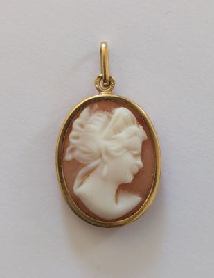 un gros plan d'un pendentif plaqué or représentant le profil d'une femme