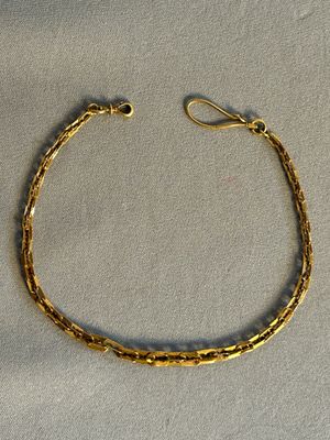 gros plan d'un bracelet en or sur une surface blanche