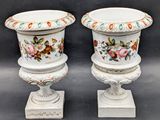 two white vases with floral designs on them sitting on top of a table