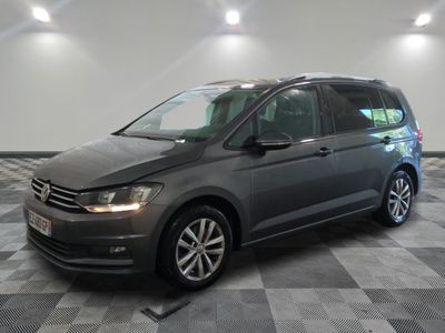 une Volkswagen Touran grise garée dans un garage au sol carrelé