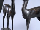 two bronze statues of a deer and a goat on a table