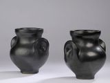 pair of black vases sitting on top of a white surface