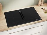 une photo d'une plaque de cuisson noire posée sur un plan de travail en bois