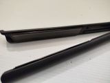 a black cell phone sitting on a table next to a black pen