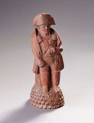 figurine représentant un homme coiffé d'un chapeau et vêtu d'un manteau, tenant un oiseau dans ses mains