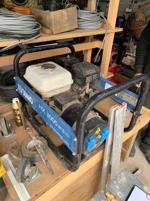 Quelqu'un travaille sur une machine dans un garage, où d'autres outils sont posés sur une étagère.