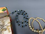 trois colliers et une boîte de perles posés sur une table
