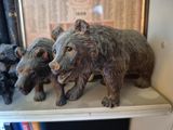 three statues of bears on a shelf next to a bookcase