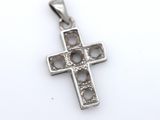 a close up of a silver cross on a white surface