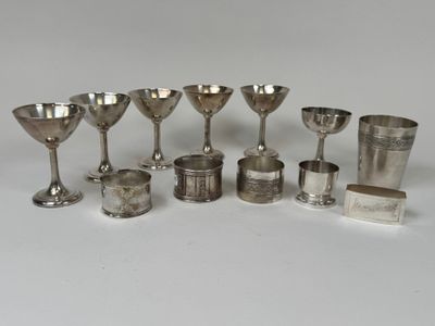 Plusieurs coupes et cuillères en argent sont alignées sur une surface blanche
