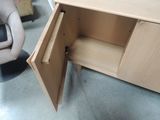 a wooden cabinet with a door open and a chair in the background