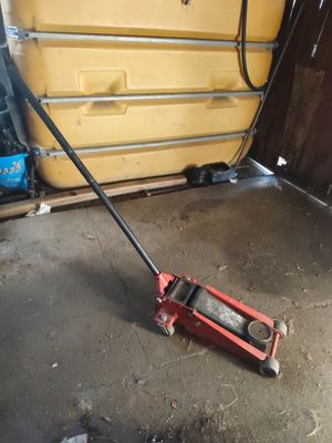 un cric rouge posé par terre dans un garage